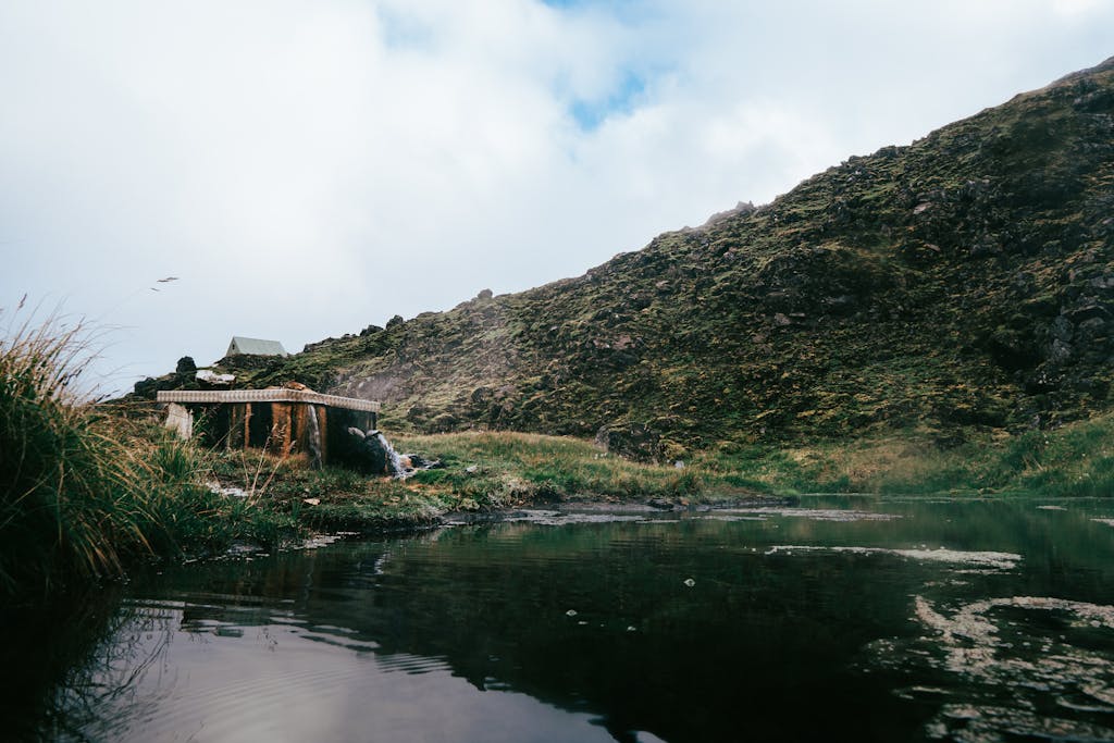 Tranquil mountainous scene in Iceland with a reflective pond and lush greenery.